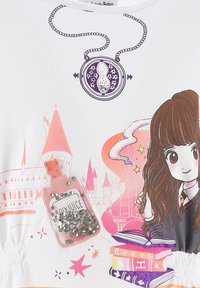 T-shirt blanc avec un design graphique comportant une horloge, un château et une fille aux cheveux foncés. Inclut une bouteille transparente avec des sequins.