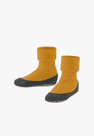 Gele gebreide sokken met een omgevouwen manchet en grijze gestructureerde zolen, voorzien van witte rubberen grips aan de onderkant voor extra grip.