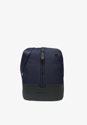 Marineblaue Umhängetasche mit einem strukturierten Stoffobermaterial und einem glatten schwarzen Lederboden; verfügt über einen mittigen Reißverschluss und ein Logodetail.