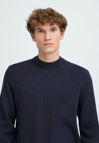 Pulover bleumarin cu guler rotund ribbed, mâneci lungi și material texturat, moale. Design simplu și clasic.