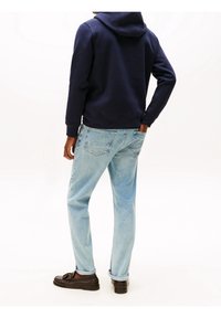 Granatowa bluza z kapturem, jasnoniebieskie dżinsy i brązowe mokasyny. Dżinsy mają luźny krój i podwinięte nogawki; bluza posiada kieszeń kangurkę.