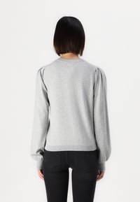 Grå sweater med puffede skuldre, rund halsudskæring og ribbet kant. Lavet af blødt materiale, tætsiddende ved taljen og med lange ærmer.