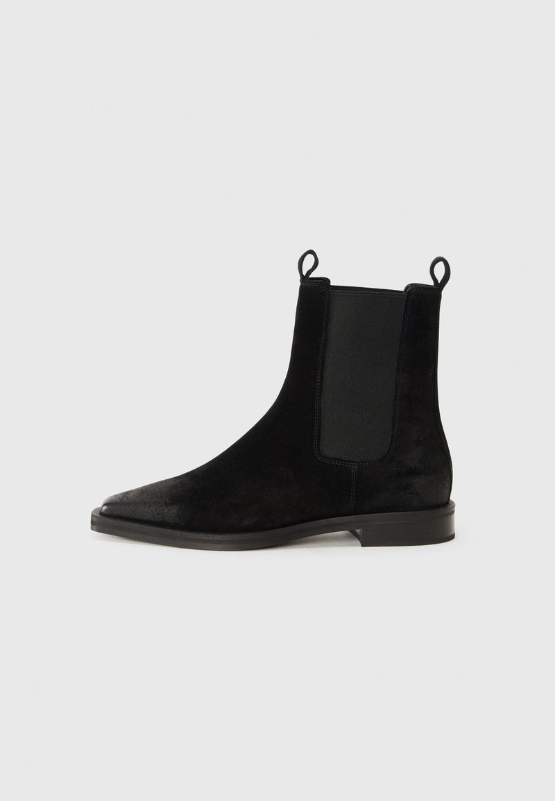 Bottines en suede noir avec un bout pointu, des panneaux latéraux élastiques et des languettes de traction ; texture lisse et petit talon carré.