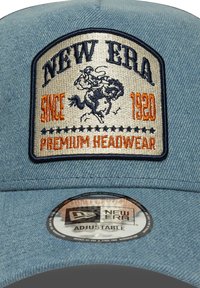 Gorra de béisbol de mezclilla en azul claro con un parche bordado que presenta "New Era", un jinete y "Desde 1920". Correa ajustable en la parte posterior.