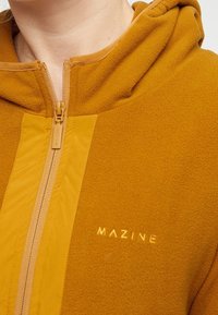 Mosterdgele fleece hoodie met een contrasterend paneel en een rits met een logo-label. Zachte textuur, ontworpen voor warmte.