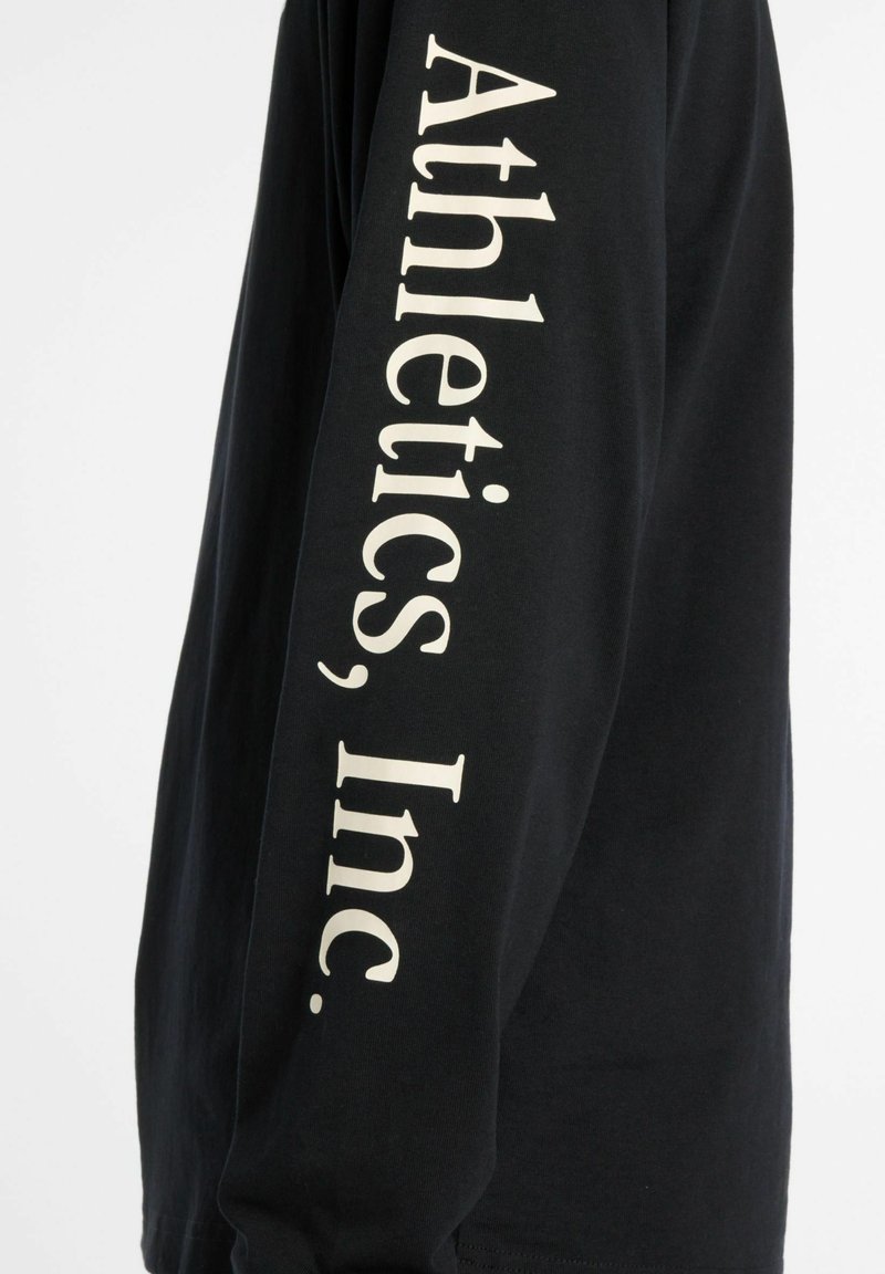 Zwart shirt met lange mouwen van katoen, met op de mouw witte tekst "Athletics, Inc." en een relaxte pasvorm.