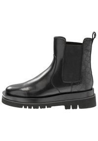 Botte Chelsea en cuir noir avec panneau élastique sur le côté, talon à motifs, languette de tirage, et semelle épaisse noire avec des rainures profondes.