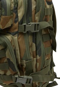 Camouflage backpack made of durable fabric featuring a mix of brown, green, and black patterns, with multiple zippers and adjustable straps.