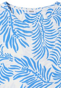 Top en tissu blanc avec motif de feuilles tropicales bleues et encolure ronde, étiqueté avec le nom de la marque "CECIL."