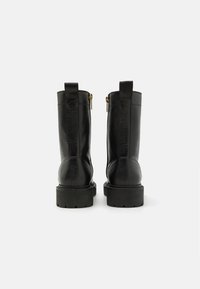 Black leather ankle boots featuring a textured finish, rounded toe, chunky sole, and gold zipper detail on the back.