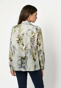 Long-sleeve blouse in lightweight fabric, featuring a floral pattern in shades of green and grey, with a back pleat and buttoned cuffs.