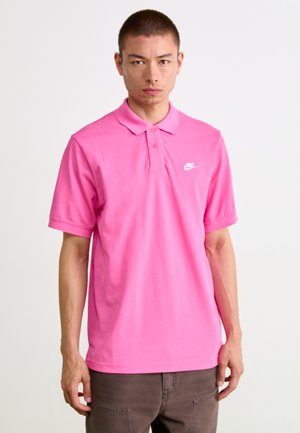 Polo shirt rose à manches courtes en coton. Équipé d'un col classique, d'une patte de boutonnage à trois boutons et d'un logo Nike blanc sur la poitrine gauche.