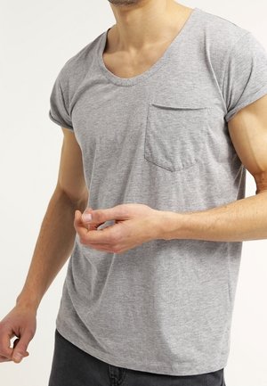 Szary t-shirt z krótkim rękawem wykonany z miękkiej bawełnianej mieszanki, z dekoltem w serek i kieszenią na piersi. Materiał ma gładką fakturę.