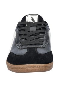 Zwart-grijze sneaker van leer en suède, met een gestructureerde zwarte tong, witte accenten en een rubberen zool in ambar kleur met spikkels.