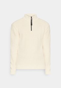 Suéter de punto color crema con cuello alto, presenta una cremallera negra y una tela texturizada; mangas y dobladillo ajustados con detalles de canalé.