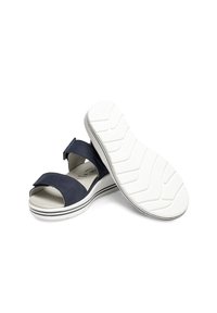 Marineblaue Sandalen mit einem weichen Obermaterial, verstellbarem Riemen und einer weißen, strukturierten Sohle mit einem Profil für besseren Halt.