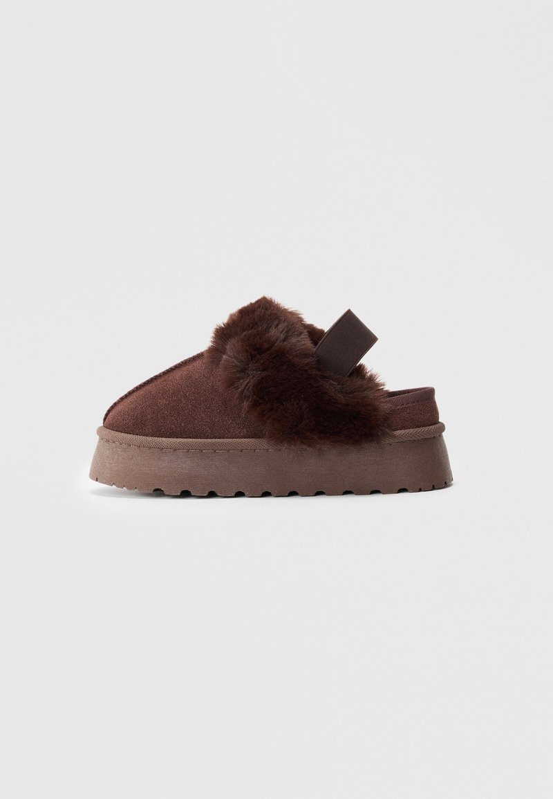 Pantofole marroni senza lacci con suola di gomma spessa, foderate in morbido peluche attorno all'apertura e con una fascia elastica sul tallone per il supporto.