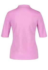 Kortärmad polo skjorta i solid rosa, med ribbad krage och mjuk textur, utformad för komfort och avslappnad stil.