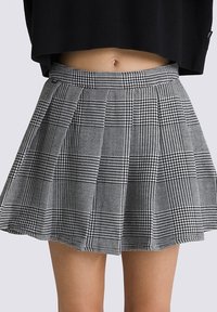 Falda plisada de cuadros en blanco y negro con una cinturilla de altura media, que presenta un tejido texturizado y un diseño acampanado.