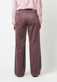 Wide-leg corduroy pants in a muted purple hue, featuring back pockets and a textured ribbed pattern, shown from the rear.