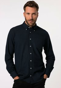 Marineblaues Hemd mit Knopfleiste, Kragen, langen Ärmeln und einer Brusttasche. Hergestellt aus strukturiertem Stoff mit weißen Knöpfen.
