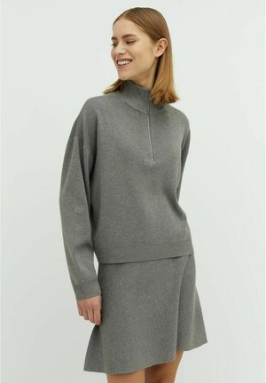 Grey knitted sweater with a high collar and a short zipper. Features long sleeves and a relaxed fit. Paired with a matching grey flared skirt.