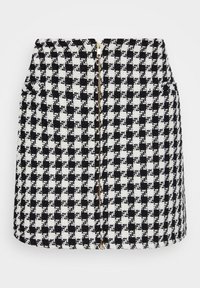Mini-jupe à motif pied-de-poule noir et blanc en tissu texturé, dotée d'une fermeture éclair frontale avec un accent doré.