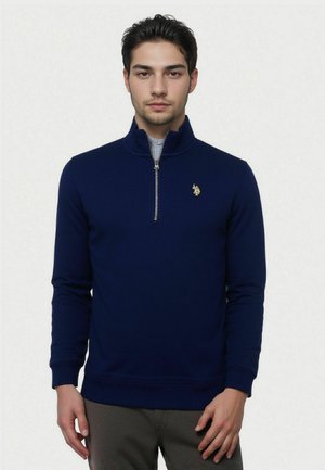 Navy blue zip-up pullover with a stand collar, ribbed cuffs, and hem; features a small gold logo on the left chest.