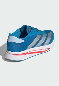 Sinine jooksuking, millel on hõbedased triibud, võrkpinnaga ülemine osa, valge vaheosa ja punane aktsent taldadel, millel on pehmendatud disain esituseks.