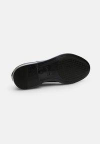 Sole in gomma nera con motivo antiscivolo. Forma arrotondata con finitura liscia e design minimalista. Accento del tacco leggermente rialzato.