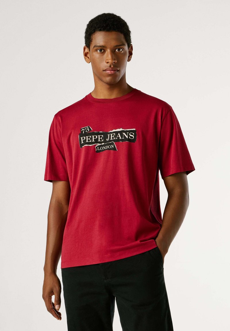 Camiseta roja de algodón con un estampado gráfico en blanco y negro que dice "73 PEPE JEANS LONDON." Manga corta y corte holgado.