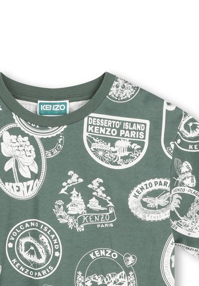 T-shirt en coton vert avec des imprimés graphiques blancs représentant diverses îles, fleurs et logos. Col rond côtelé et manches courtes.