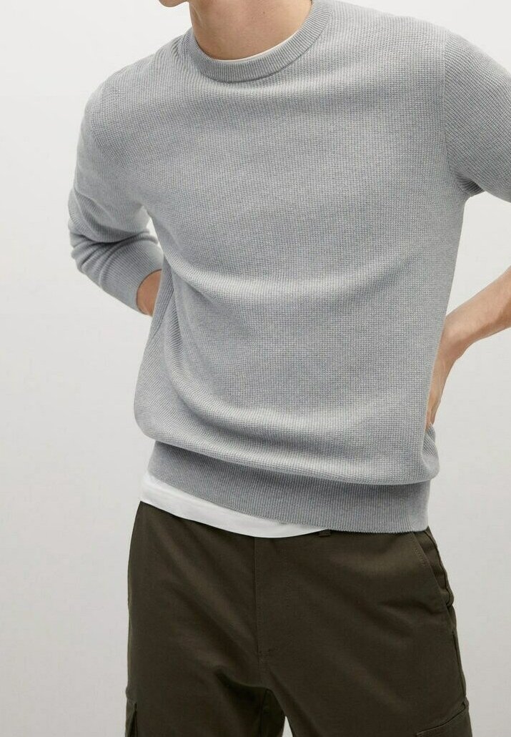 Helles graues, geripptes Strickpullover mit Rundhalsausschnitt und langen Ärmeln, übereinander getragen über einem weißen Hemd, kombiniert mit olivgrünen Hosen.