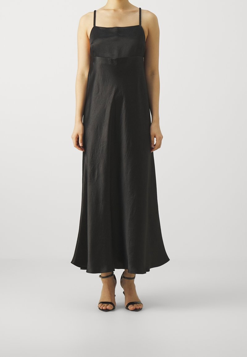 Czarna maxi sukienka na cienkich ramiączkach, wykonana z lekkiej, fakturowanej tkaniny. Gładki gorset przechodzący w rozkloszowaną spódnicę, w zestawieniu z czarnymi sandałami.