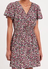 Robe florale avec un fond noir orné de motifs floraux colorés en rose, blanc et bleu sarcelle. Manches courtes à volants et taille élastique.