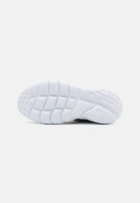 Suela blanca de una zapatilla con un patrón de agarre texturizado y segmentos elevados; líneas limpias con una forma elegante y flexible.