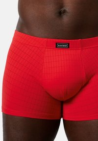 Røde trunk shorts lavet af strækbart materiale, der har et rutenetmønster, en blød elastisk talje med et sort logo tag og en tætsiddende pasform.