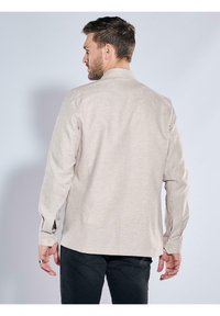 Beige Langarmhemd aus weichem Stoff, mit klassischem Kragen, Knopfmanschetten und geradem Schnitt. Rückansicht dargestellt.