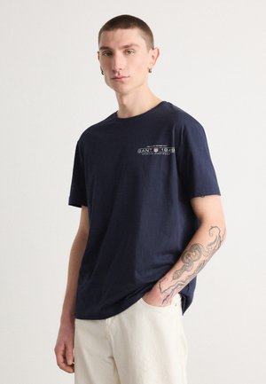 Navy blue cotton t-shirt featuring a small white print with "GANT 1949" embroidery on the chest. Short sleeves and crew neck design.
