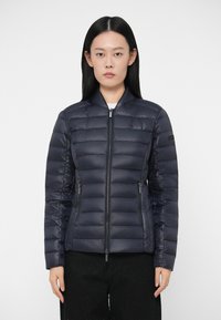 Ναυτικό πλύσιμο μπουφάν με οριζόντιες ραφές, μπροστινό φερμουάρ και δύο πλαϊνές τσέπες. Ελαφρύ, κομψό σχέδιο με όρθιο γιακά και ελάχιστους μεταλλικούς εξαρτήματα.