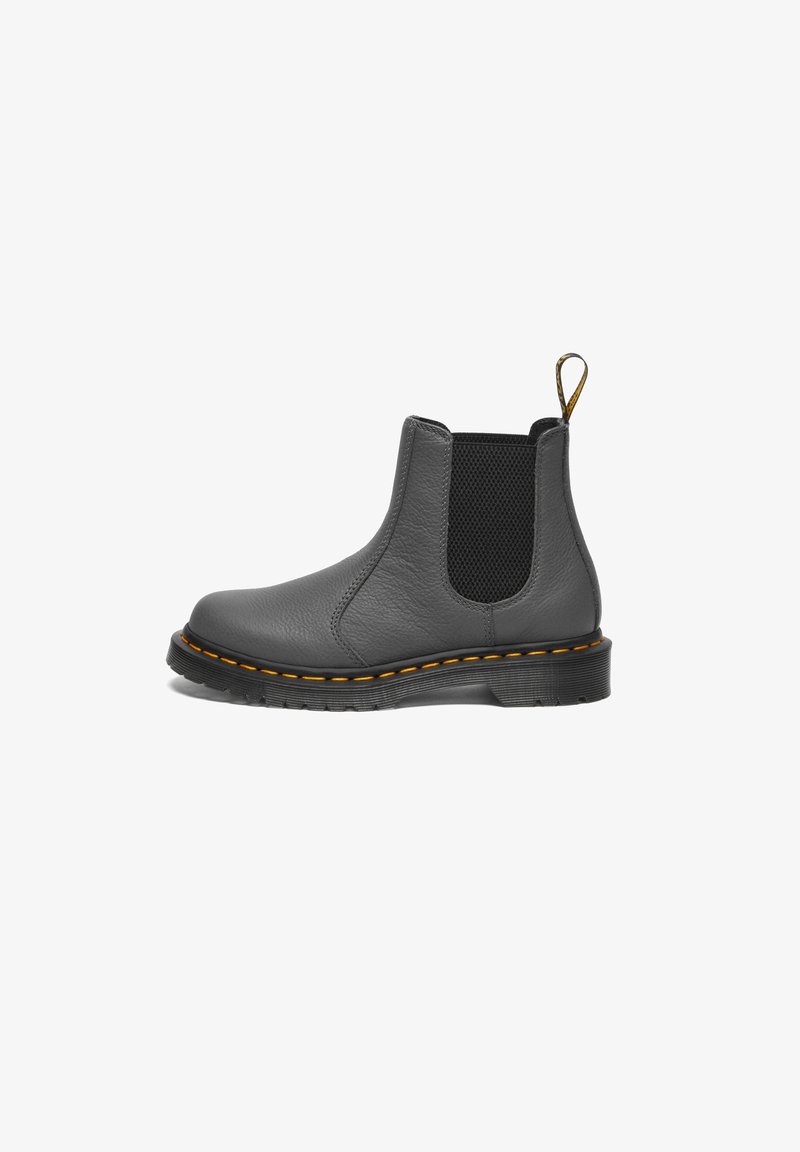 Bottine Chelsea en cuir noir avec panneau latéral élastique, coutures jaunes sur la semelle et languette de tirage au talon sur fond blanc.