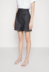 High-waisted denimshorts in een donkere was met twee voorzakken, knoopdetails en een gestructureerd ontwerp, gestyled met witte sandalen met banden.