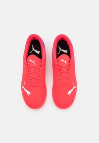 Scarpe da ginnastica di un vivace colore rosso, con una superficie liscia, dotate di un logo bianco Puma e un'accente blu sul tallone. Design con lacci e dettagli a coste.