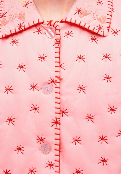 Ροζ ύφασμα με κόκκινα κεντητά μοτίβα αστεριών, ραμμένο γιακά με σχέδια καρδιών και τρία διαφανή κουμπιά στη μέση.