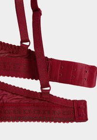Bordeauxroter Bralette mit verstellbaren Trägern, strukturiertem Stoff mit gewellten Kanten und einem Haken-Ösen-Verschluss mit drei Einstellmöglichkeiten.