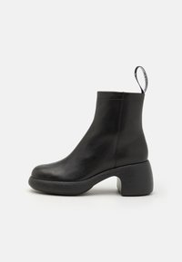 Sorte lær ankle boot med rund tå og bred blokkhæl. Har en trækflik og glat tekstur med minimalistisk design.