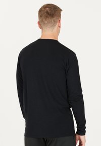 Svart långärmad tröja i mjukt, lätt tyg. Har en rund halsringning och en avslappnad passform. Bakifrån syns minimal detaljering.