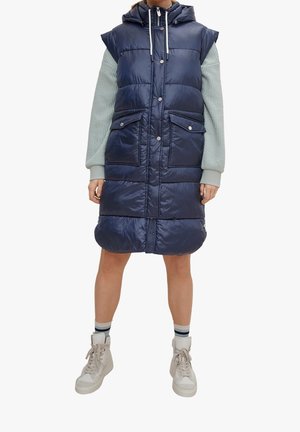 Marineblaue gesteppte Weste mit Kapuze, Druckknopfverschluss, Fronttaschen und gestepptem Design. Die Ärmel bestehen aus einem texturierten hellblauen Material.