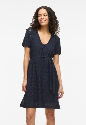 Navy blue dress made of lace with a V-neck, short sleeves, and a tied waist. Features diamond cut-outs and a flared hem.