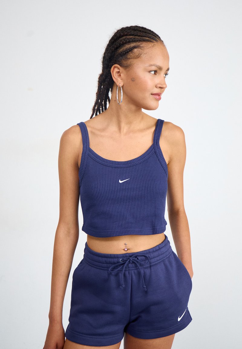 Námořnický pruhovaný crop top s širokými ramínky a malým bílým logem Nike, doplněný o námořnické šortky s elastickým pasem, které mají šňůrku a logo.